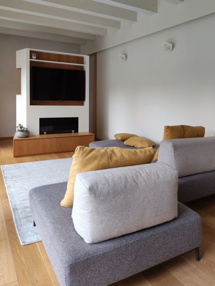 spazio living con divani moderni e arredo multifunzione in legno di rovere e finitura laccata bianca, attrezzato per TV e camino